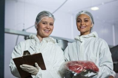 Portrait of female butchers maintaining records on clipboard at meat factory