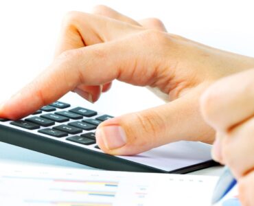 Hands of accountant with calculator and pen. Accounting background.