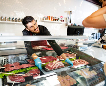 Female customer against raw meat stall section in food store, close up